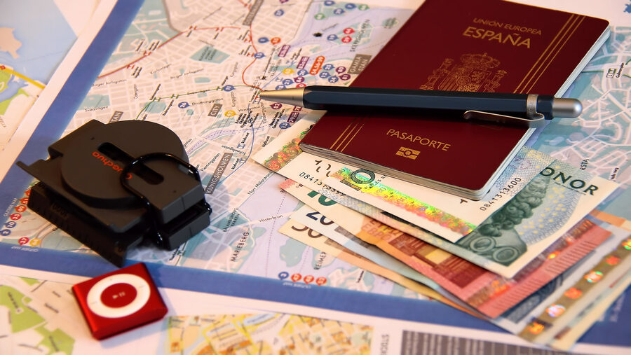 Travel documents laid out for a trip: a passport, map, pen and currency